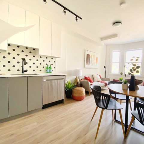 A modern kitchen with white cabinets and a black and white backsplash.