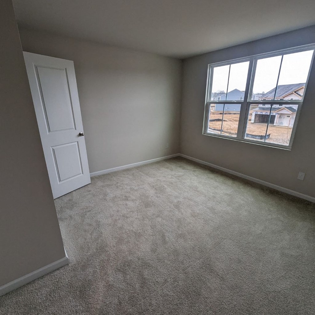 an empty living room with a window and carpet
