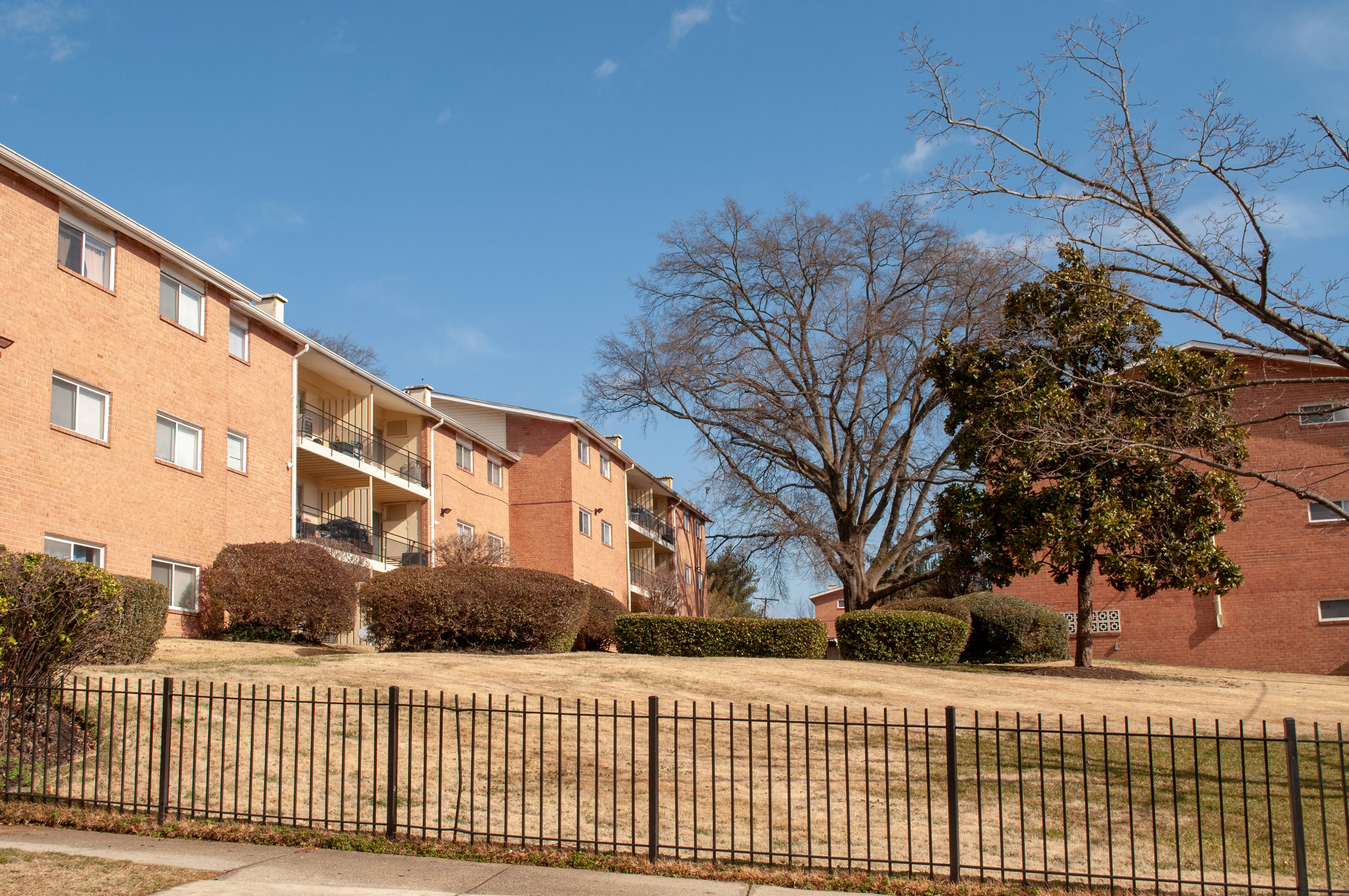 Neatly landscaped apartment grounds with green lawns, trees, and seasonal plants