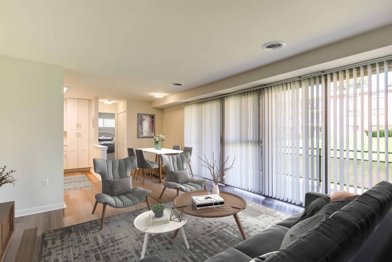 A living room with a grey couch, a white coffee table, and a dining table with chairs.