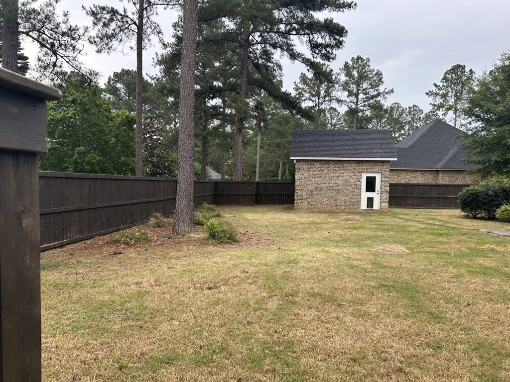 a backyard with a fence and a small house