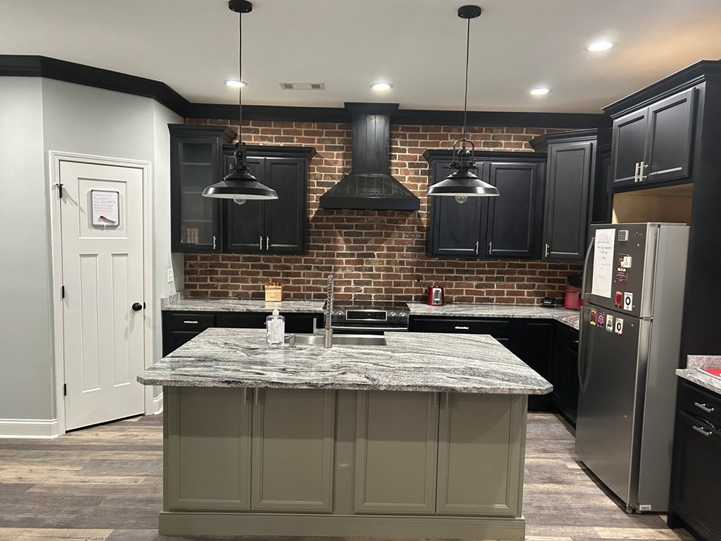 a kitchen with black cabinets and a brick wall
