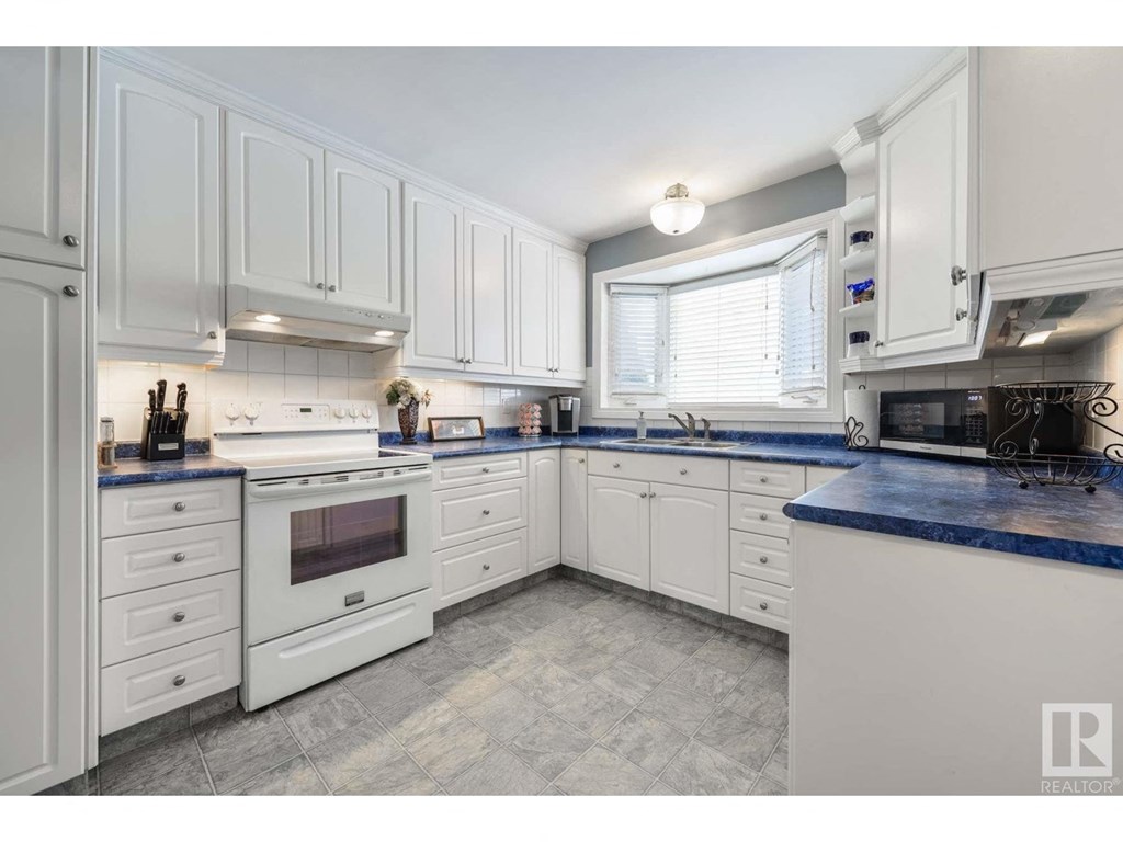 a large white kitchen with white cabinets and blue counter tops