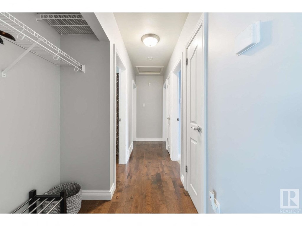 a long hallway with white closets and wood floors