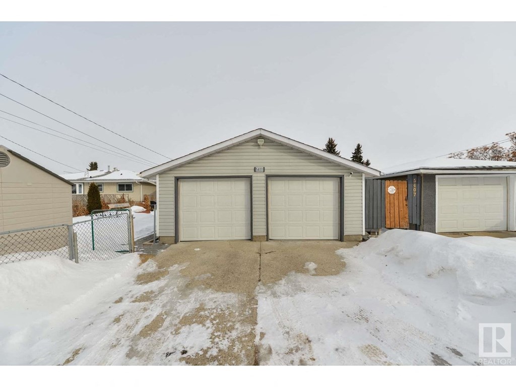 a home with two garages and a driveway in the snow