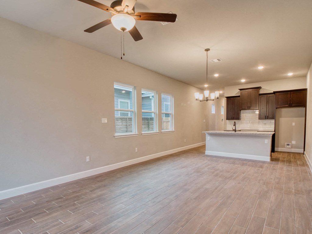 an empty living room and kitchen with a ceiling fan