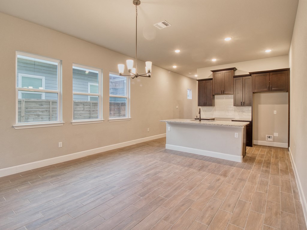 an empty living room with a kitchen with a sink and a refrigerator