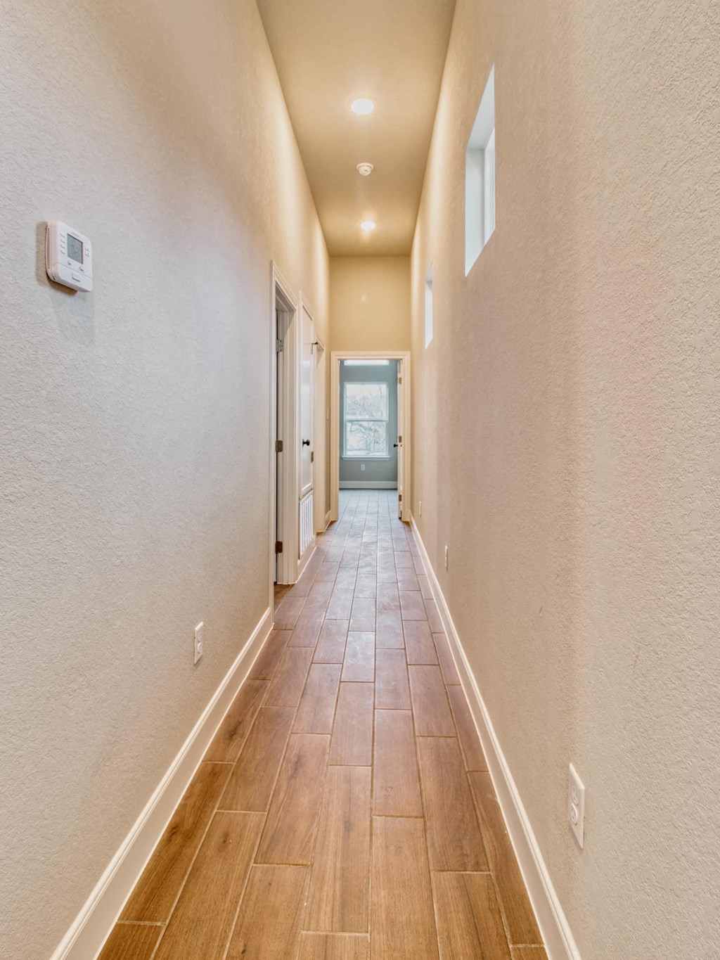 a long hallway with wood floors and white walls and doors