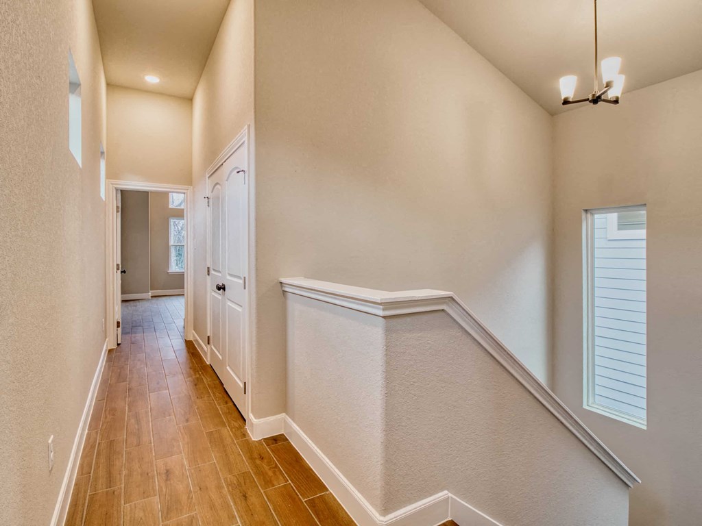 a hallway with white walls and wood floors and a white door