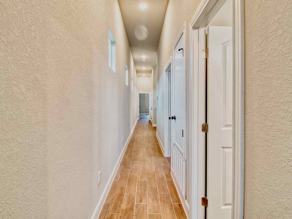 a long hallway with white walls and wood floors
