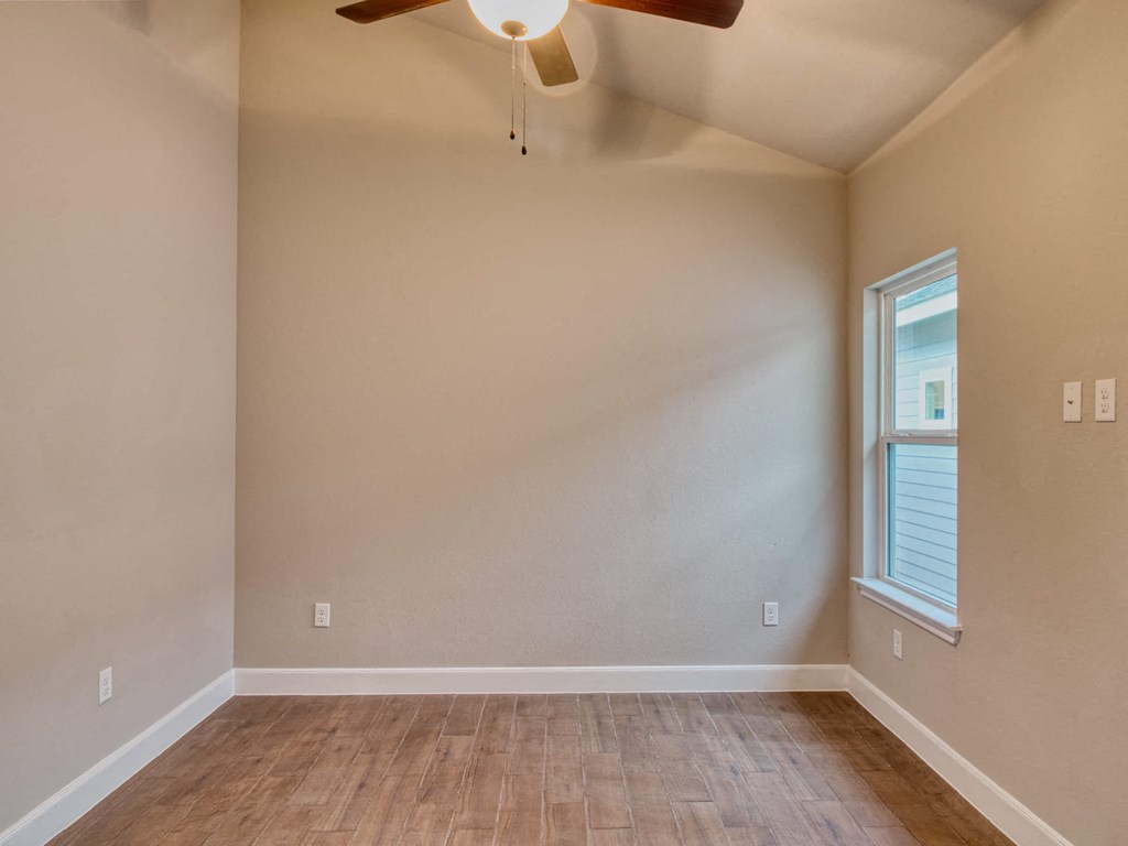an empty living room with a ceiling fan and a window