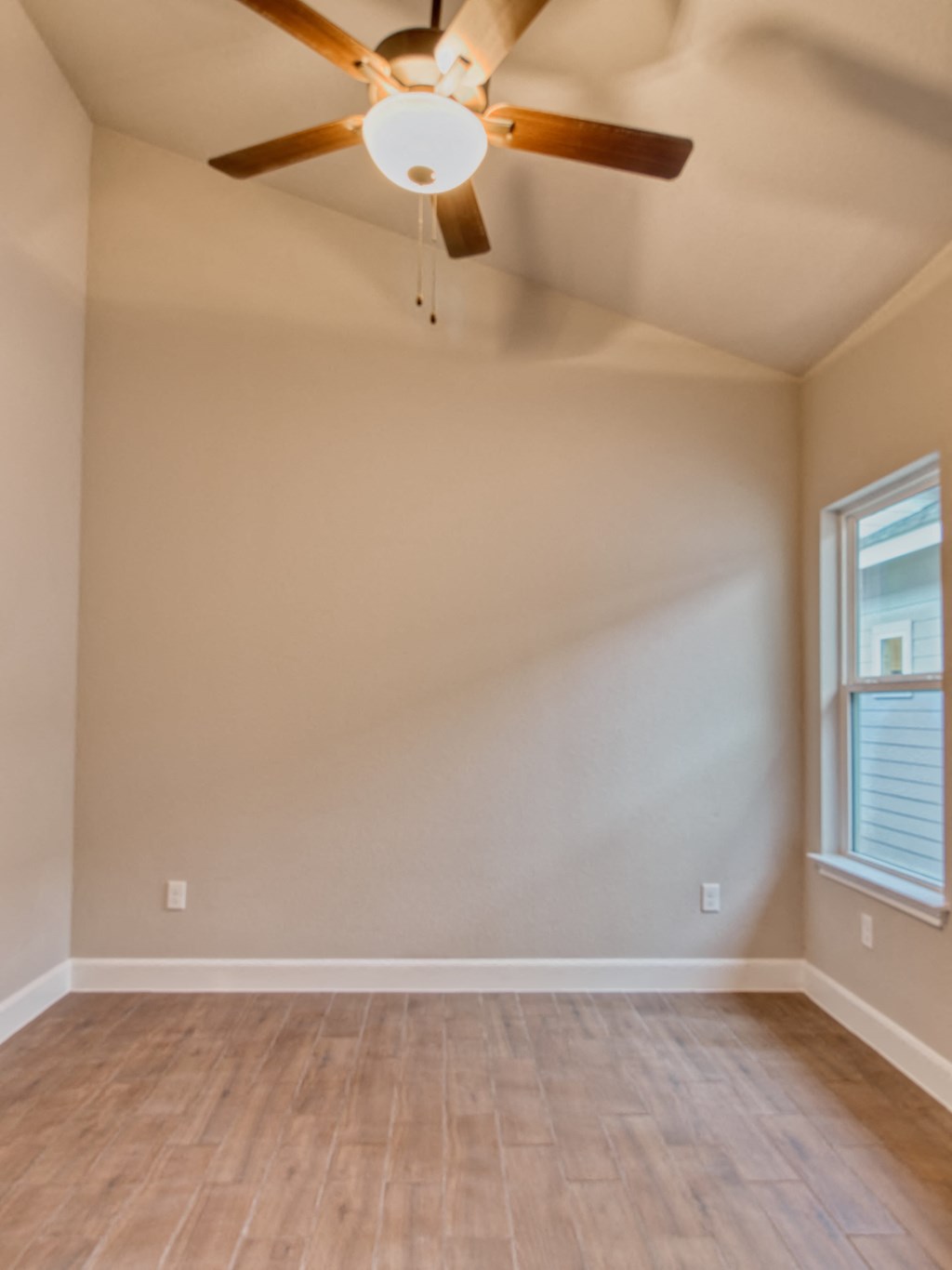 an empty living room with a ceiling fan and a window