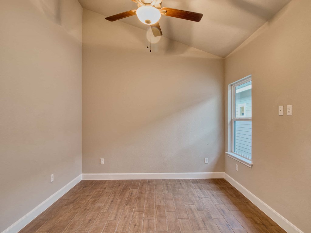 the spacious living room with hardwood floors and a ceiling fan