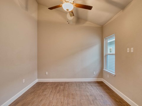 the spacious living room with hardwood floors and a ceiling fan