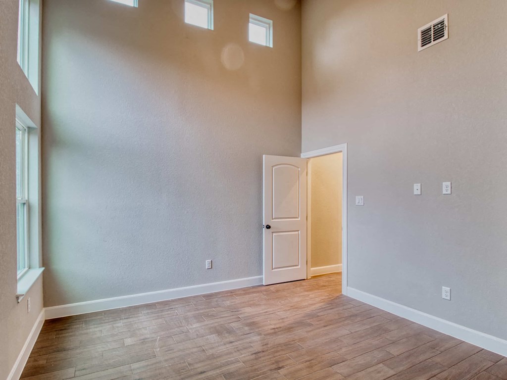 an empty living room with a door and a wooden floor
