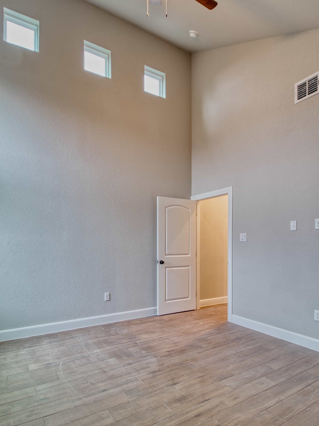 an empty living room with a door to a hallway and a wooden floor