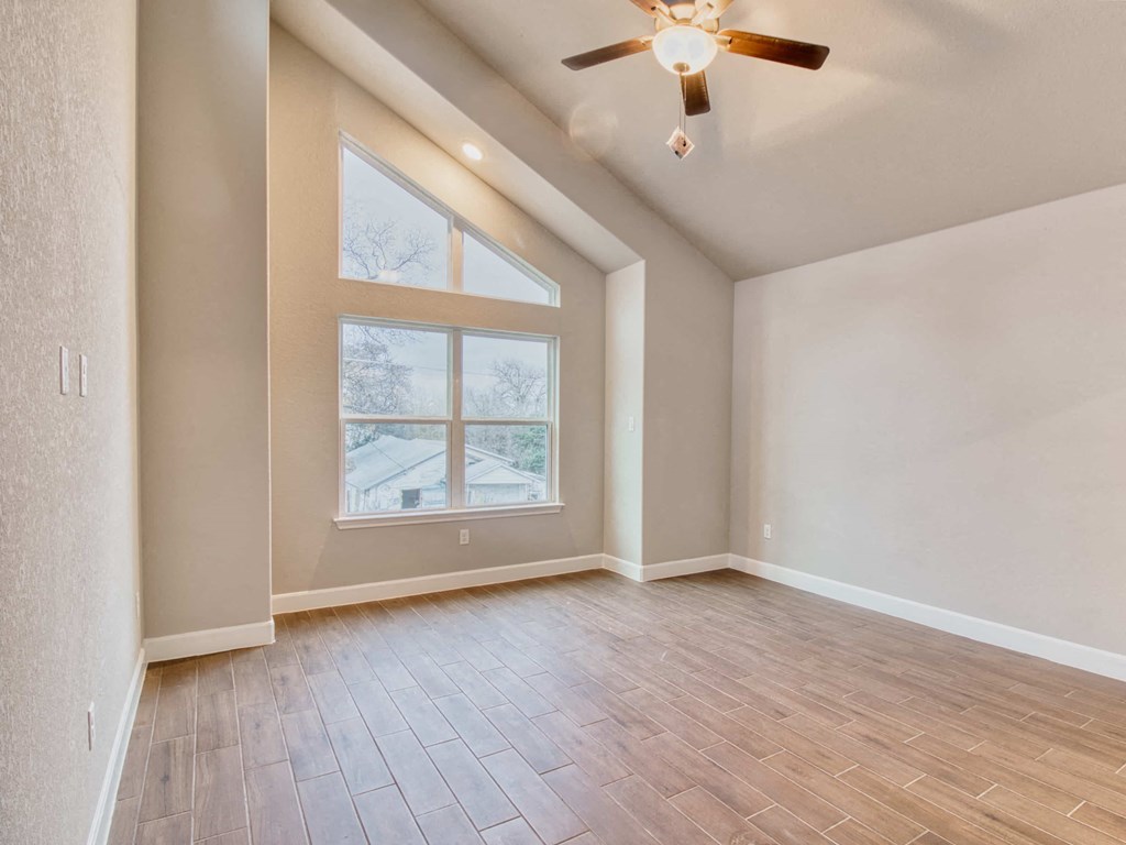 an empty living room with a large window and wooden floors