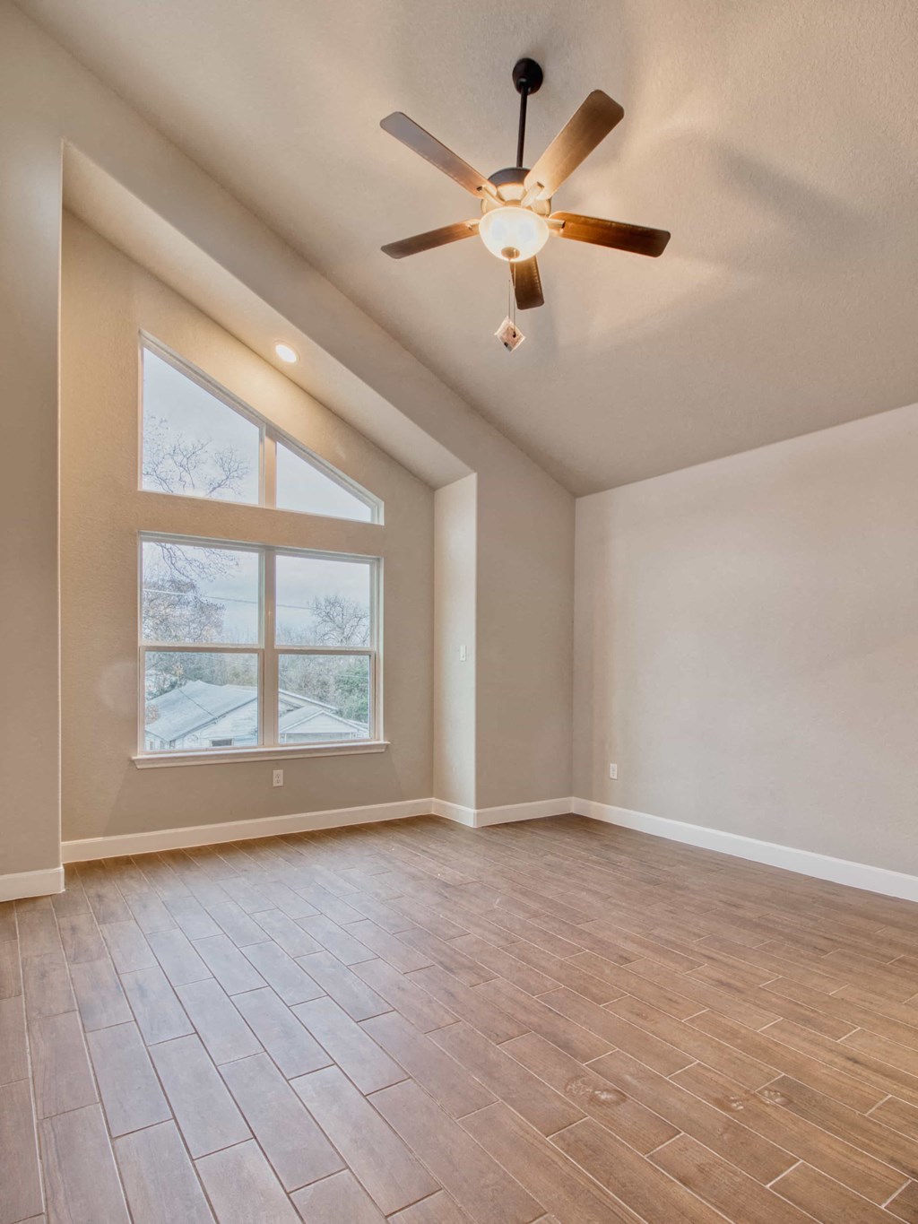 the spacious living room with a large window and a ceiling fan