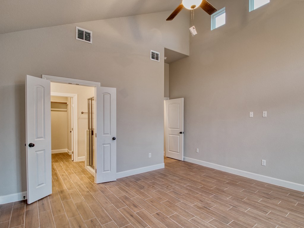 an empty living room with doors and a ceiling fan