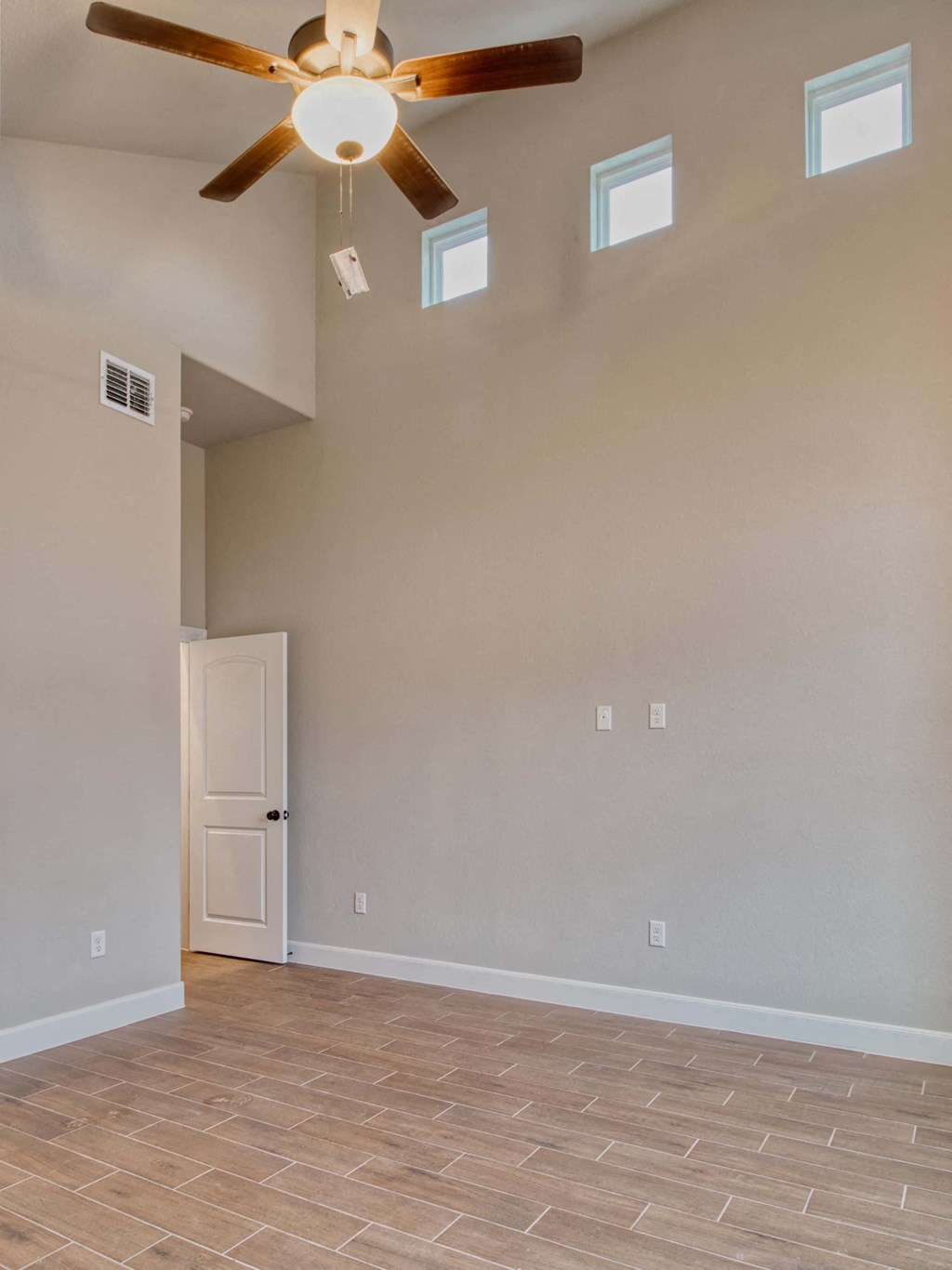 an empty living room with a ceiling fan