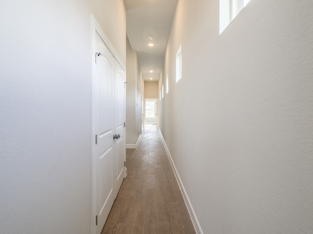 a long hallway with white walls and white closets and doors