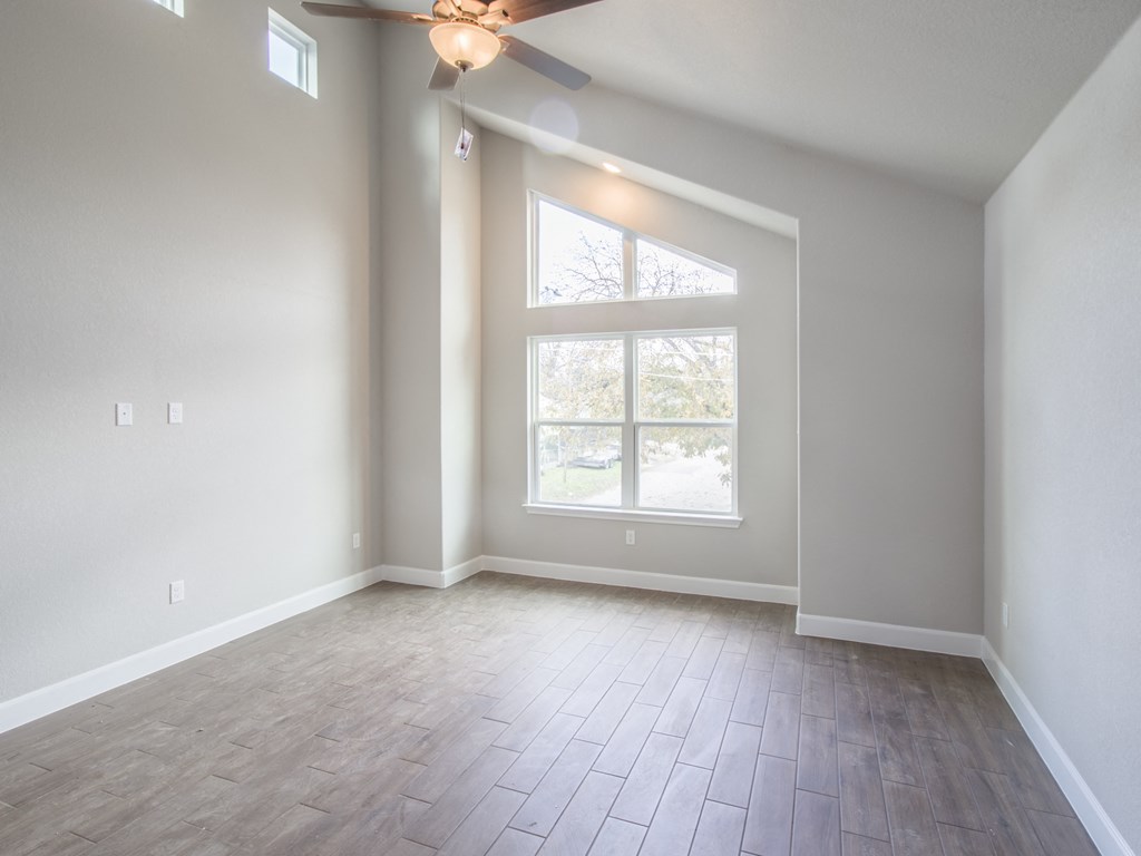 an empty living room with a large window and wood flooring