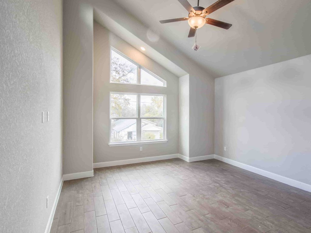 an empty living room with a large window and a ceiling fan