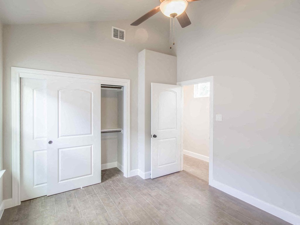 an empty living room with white doors and a ceiling fan