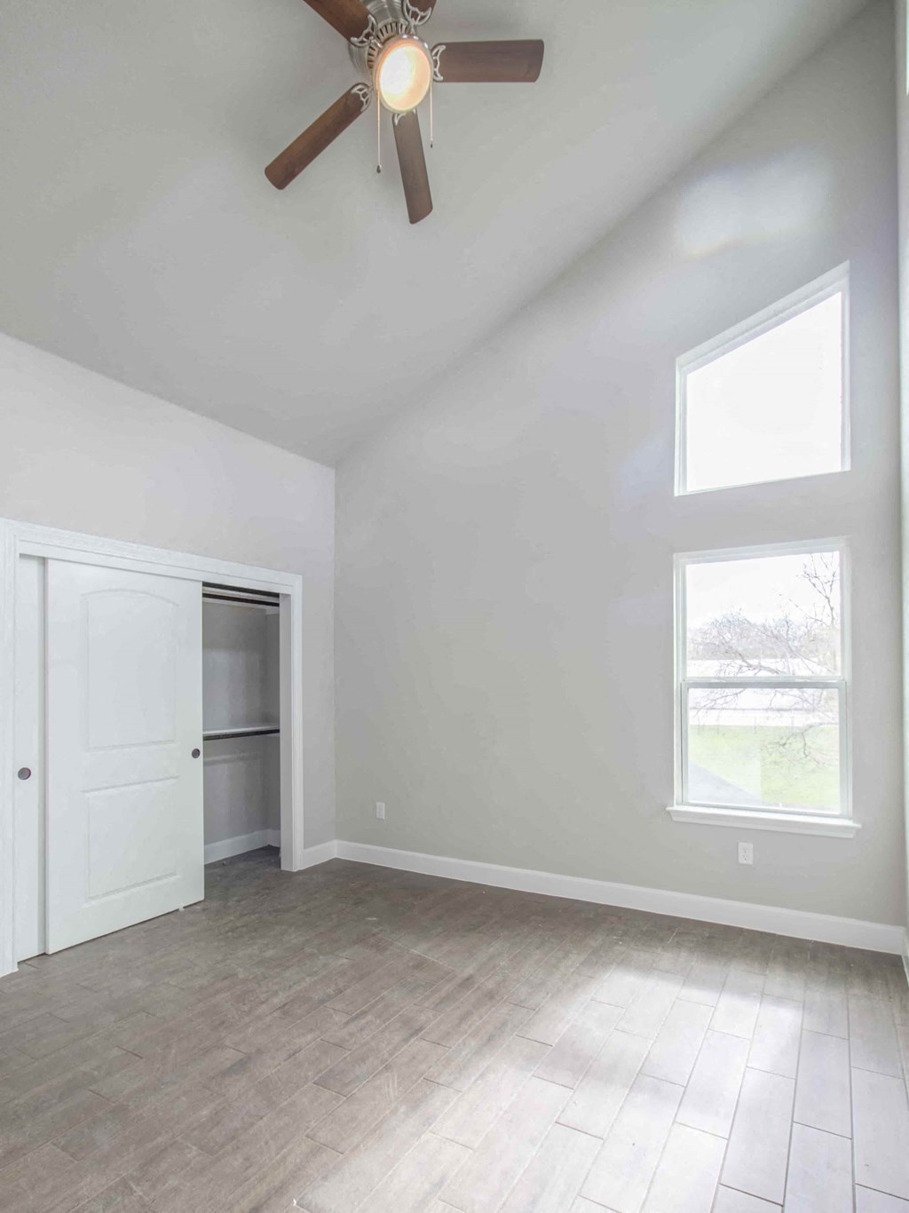 an empty living room with a ceiling fan and a closet