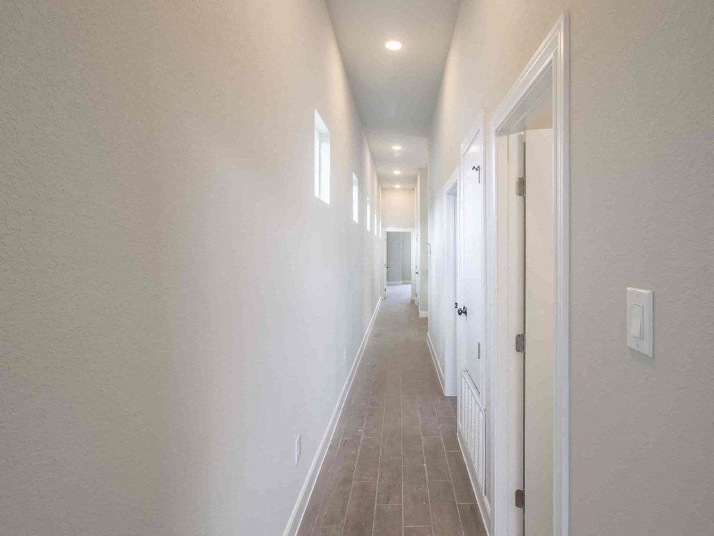 a long hallway with white walls and a white door