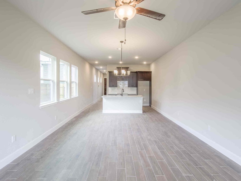 an empty living room and kitchen with a ceiling fan