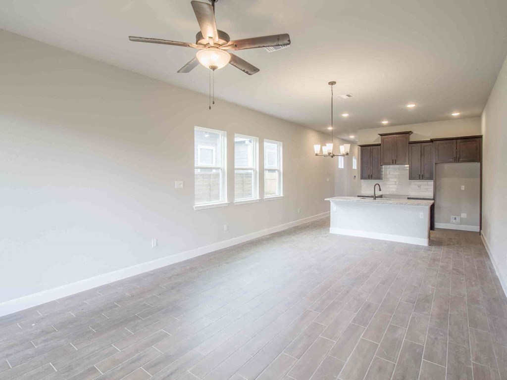 an empty living room and kitchen with a ceiling fan