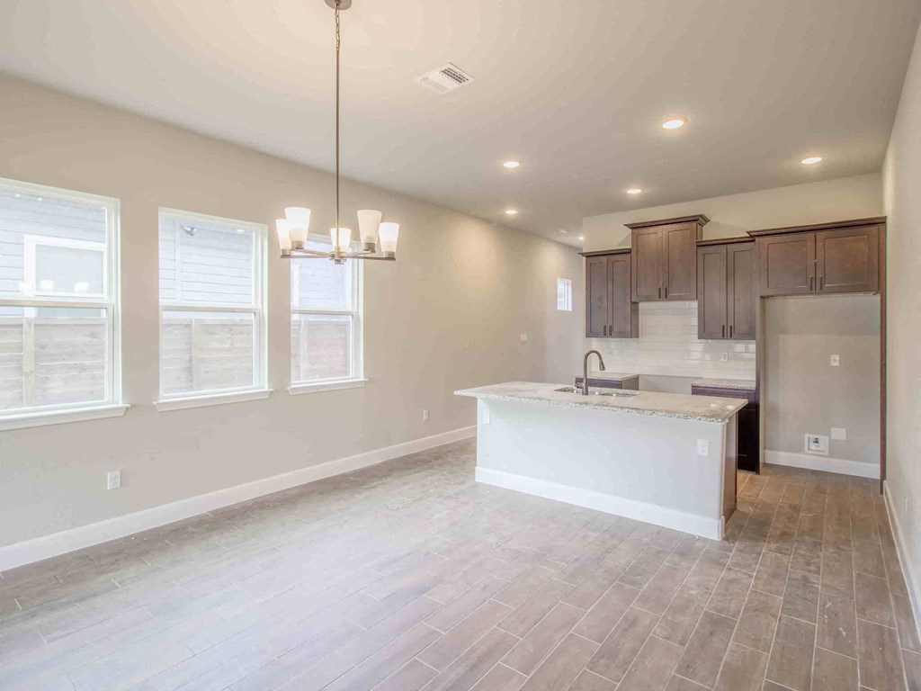 an empty kitchen and dining room with a refrigerator and a sink