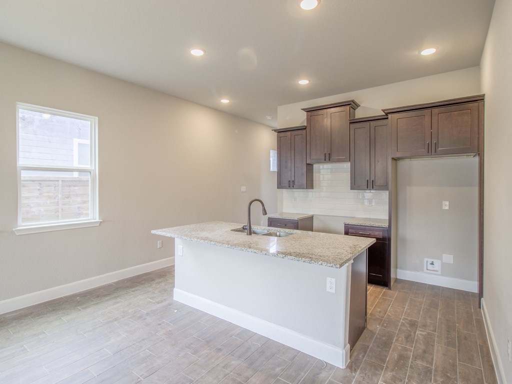 an empty kitchen with a large island and a stainless steel refrigerator