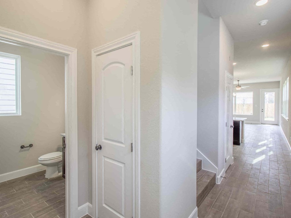 a bathroom with a white door and a toilet in a hallway