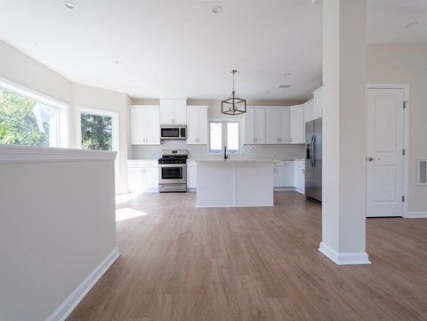 A modern kitchen with white cabinets and a wooden floor.