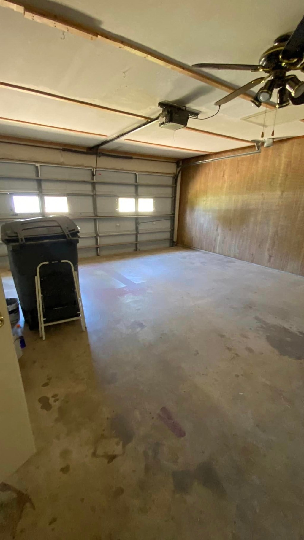 an empty garage with a dirty floor and a trash can