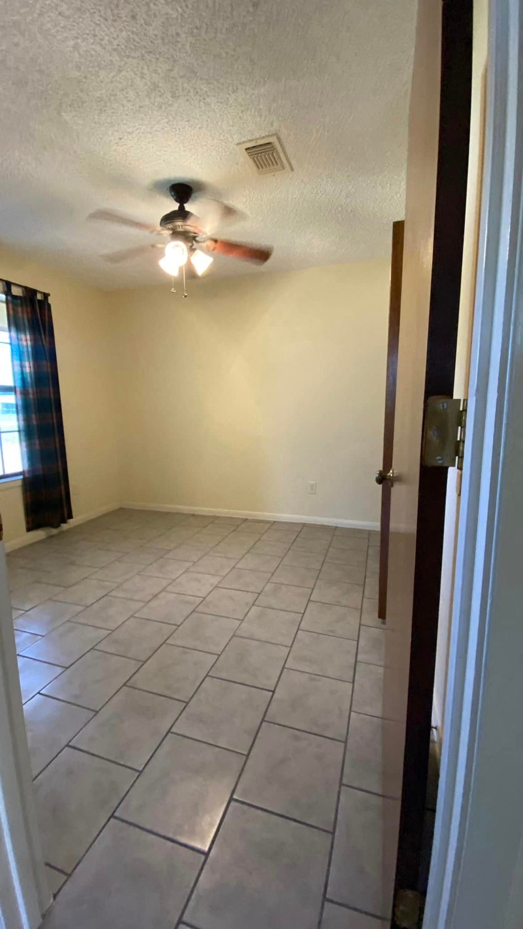 an empty living room with a ceiling fan and a tiled floor