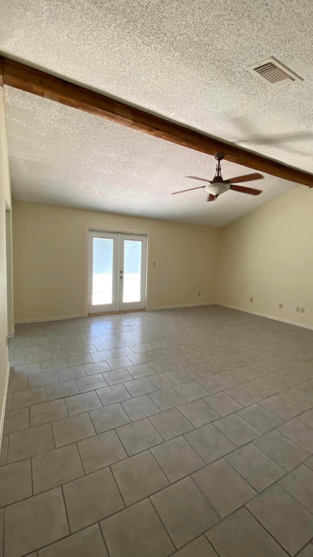 an empty living room with a ceiling fan and a tiled floor