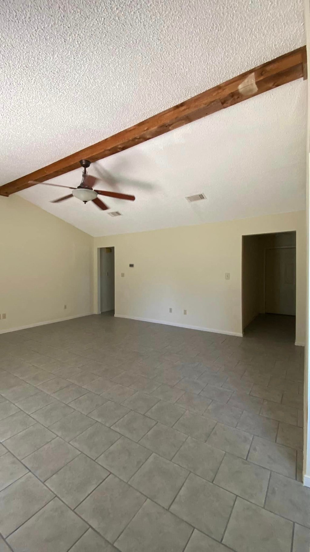 an empty living room with a ceiling fan and a tiled floor