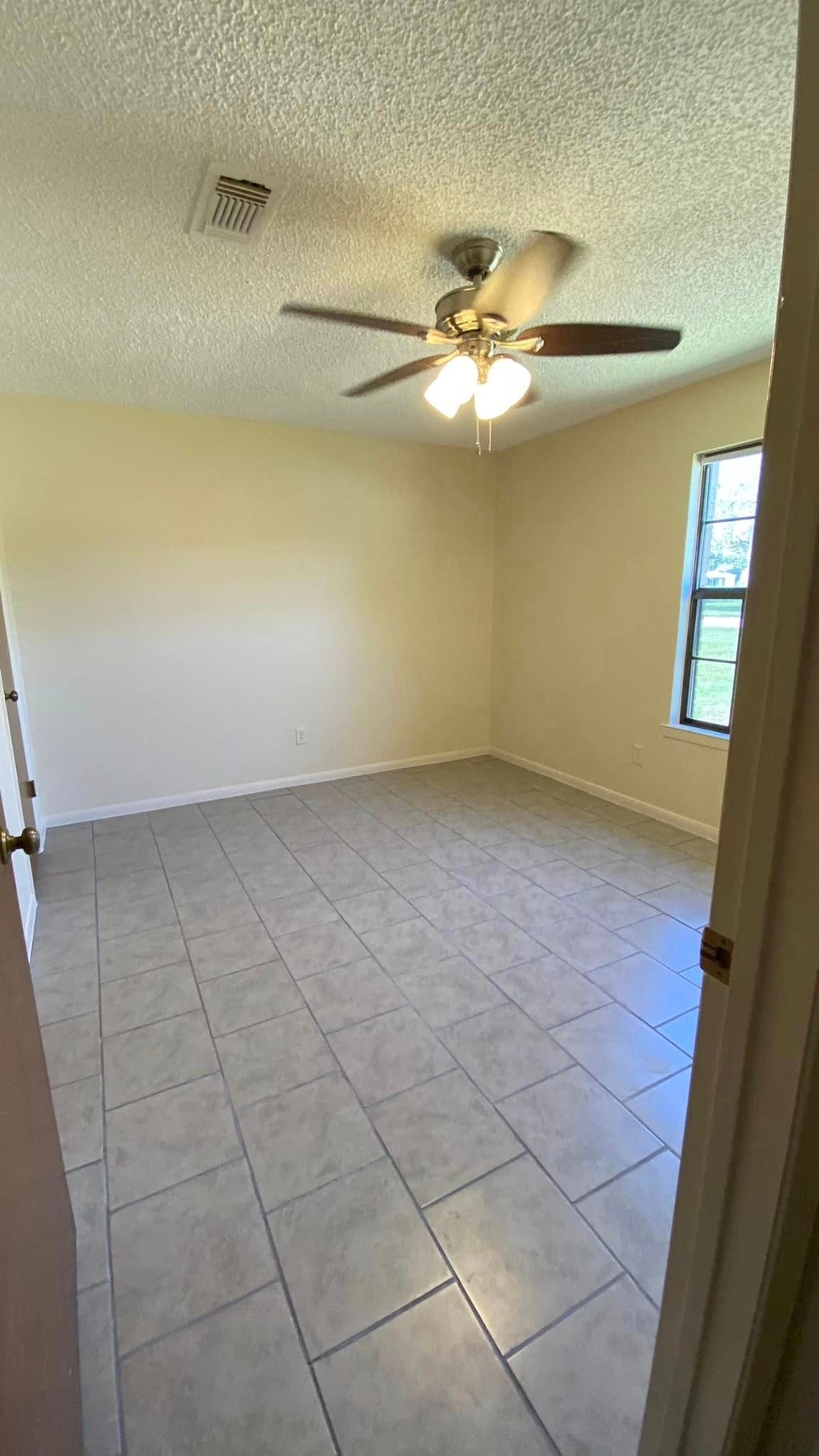 a empty room with a ceiling fan and a tiled floor