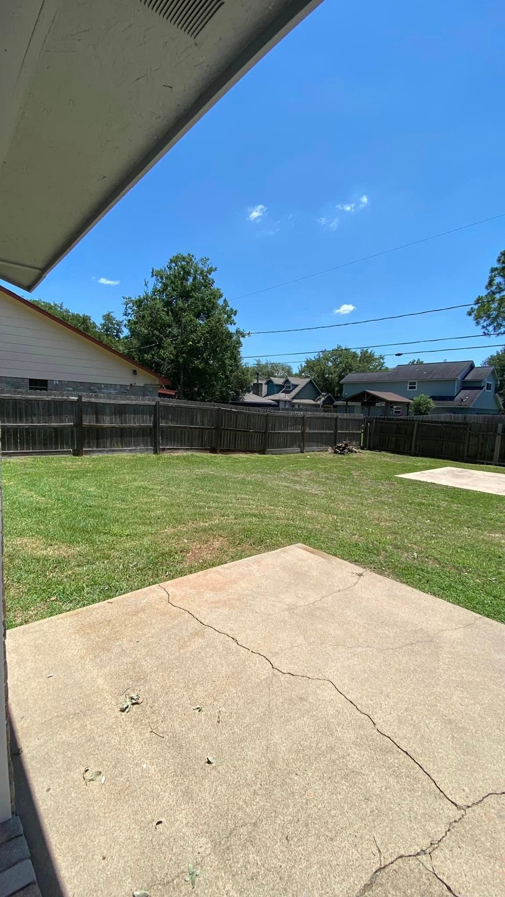 a backyard with a fence and a yard with a patio