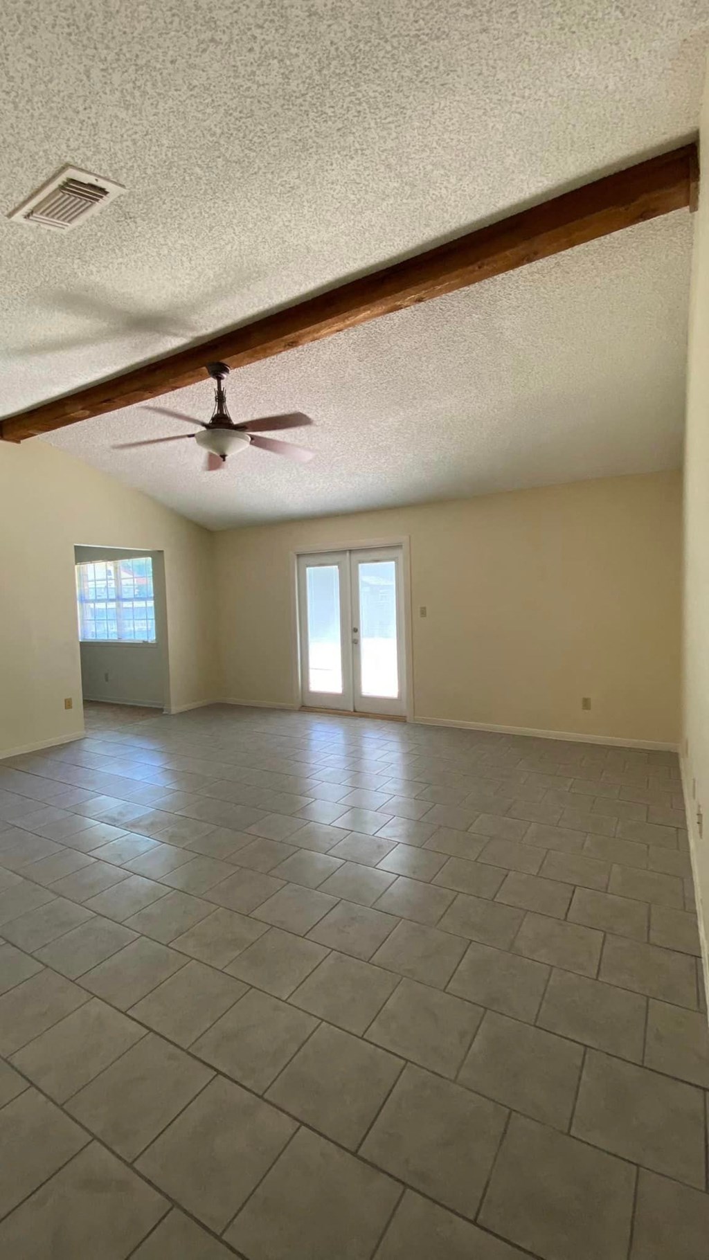 an empty living room with a ceiling fan and a tiled floor