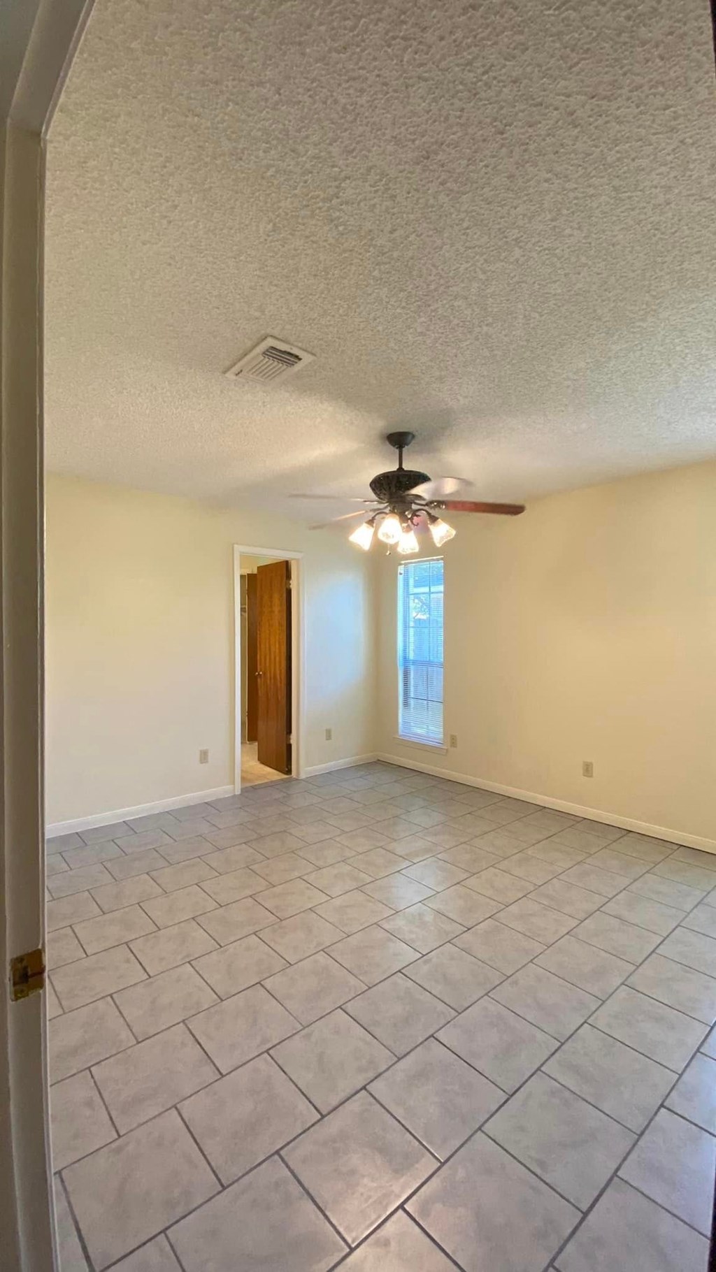 an empty living room with a ceiling fan and a tiled floor