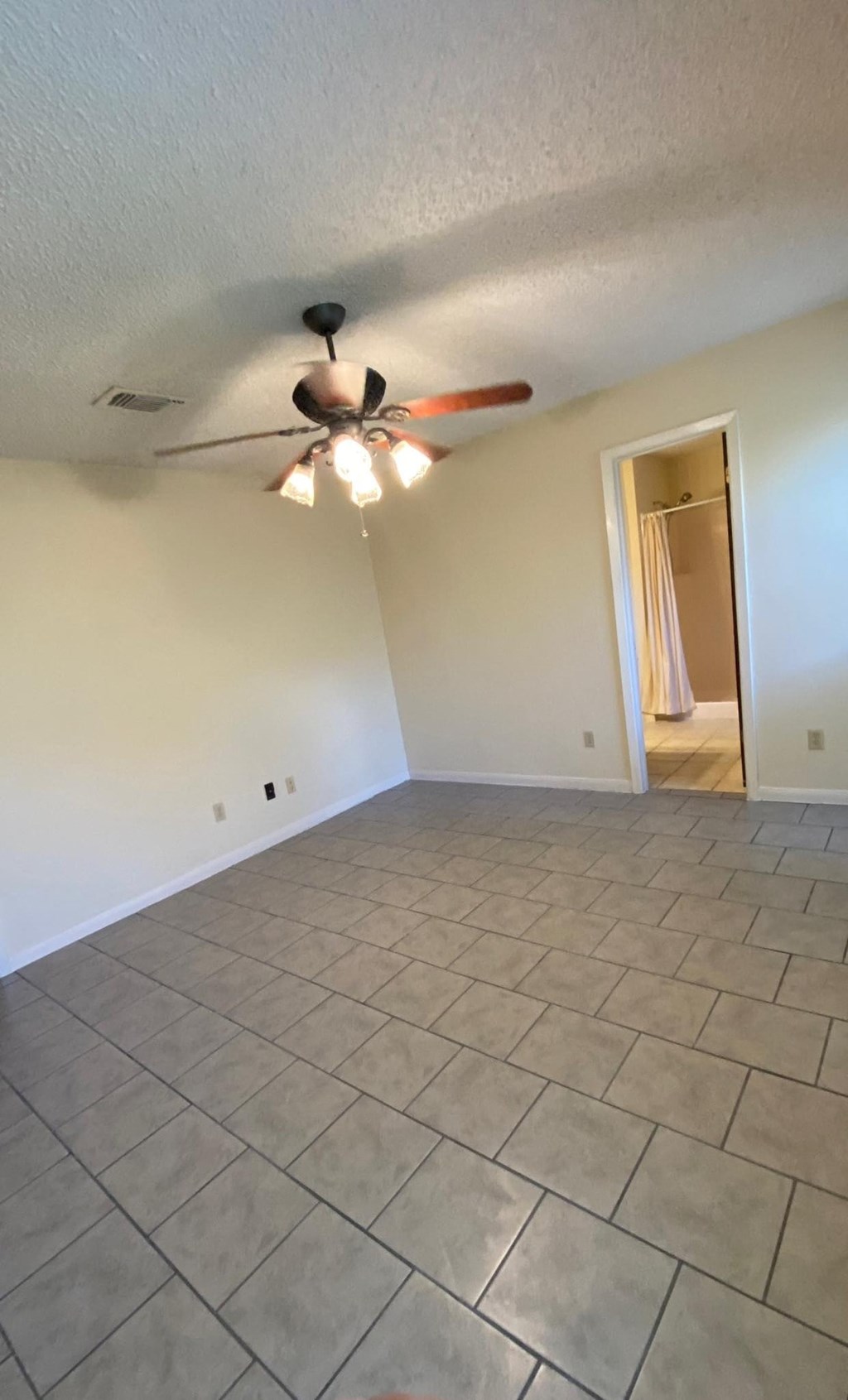 an empty living room with a ceiling fan and tile floor