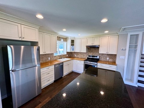 a kitchen with white cabinets and stainless steel appliances