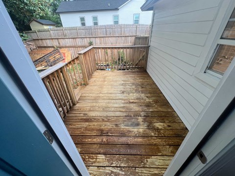 A wooden deck with a white house in the background.