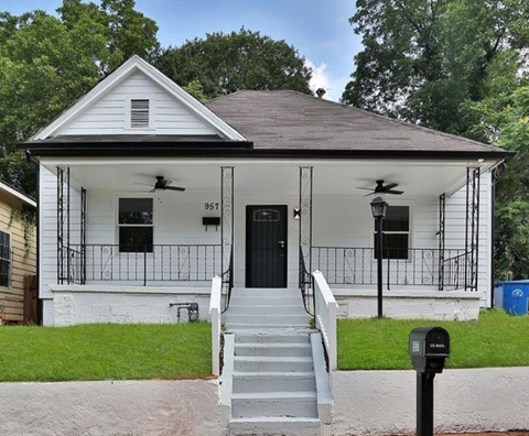 a small white house with a black door and stairs