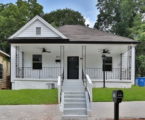 A white house with black railings and a black door.