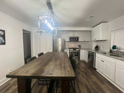A modern kitchen with a wooden table and white cabinets.